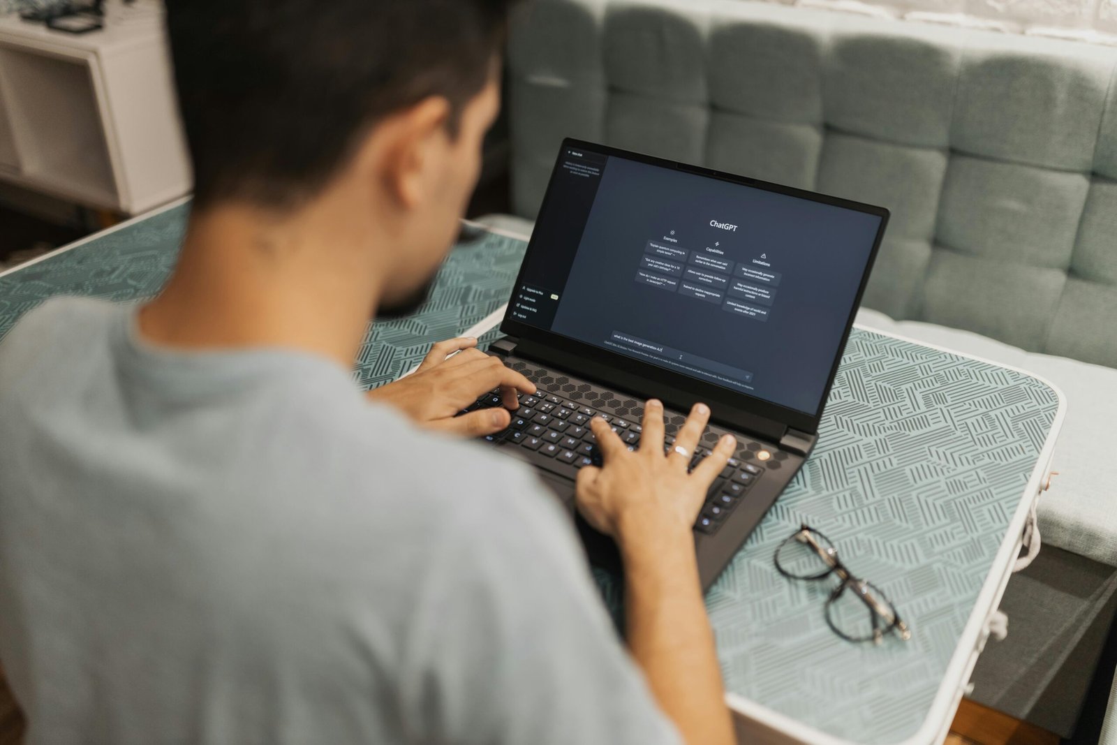 A man working on a laptop displaying ChatGPT's interface in an indoor setting.